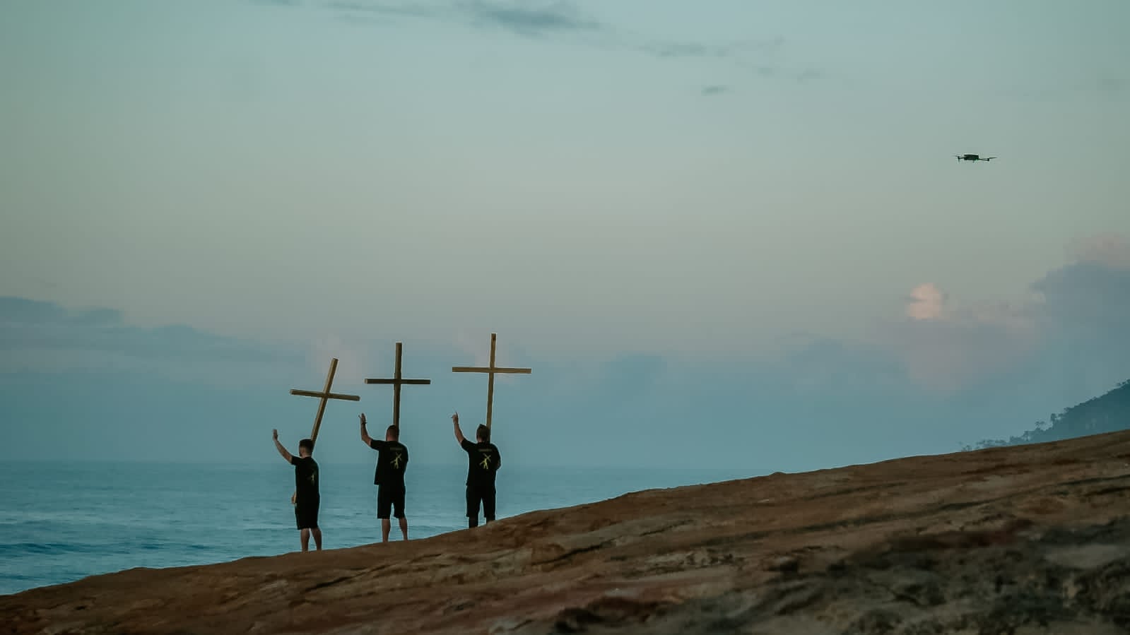 Missionários com cruzes diante do mar